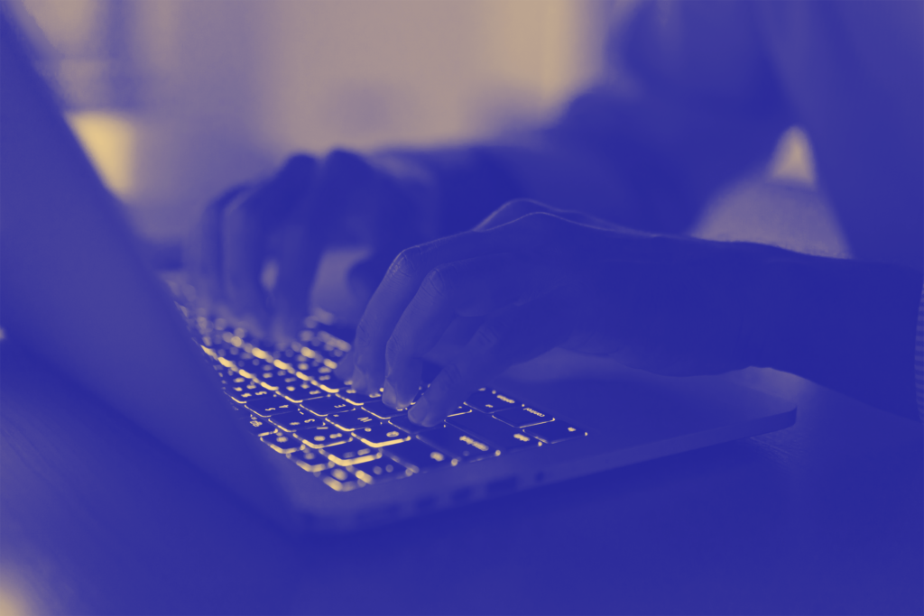 A close-up of hands typing on a laptop keyboard