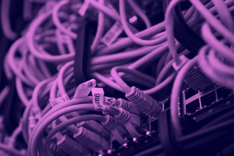 A close-up view of tangled network cables with a purple tint.