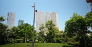 A bright day showcasing a modern cityscape with tall buildings in the background and lush greenery in the foreground.