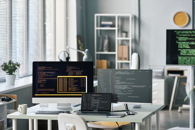 A stylish workspace featuring multiple monitors displaying code on a desk.