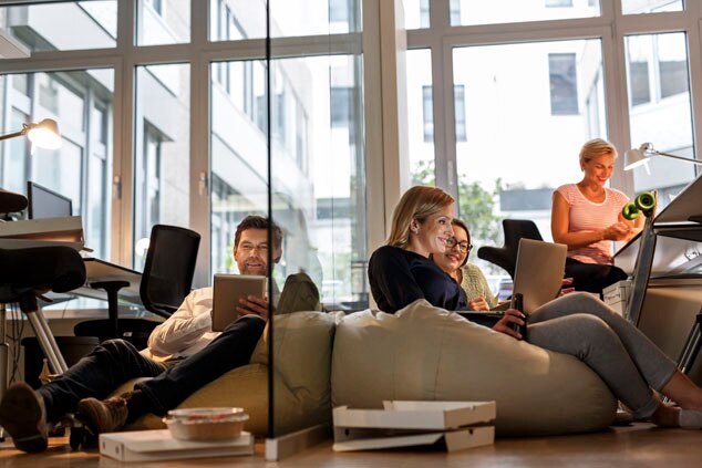 A group of people relaxing in a modern office environment,engaging with devices and enjoying their time together.