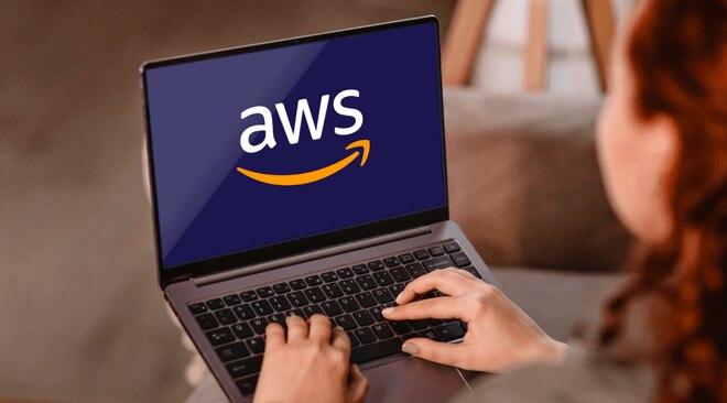 A person using a laptop with the AWS logo displayed on the screen.