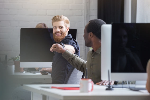 Two office colleagues sharing a fist bump in a modern workspace