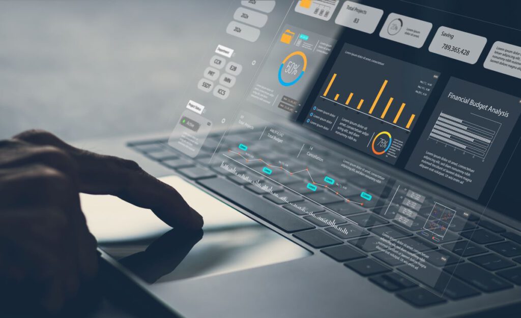 Hand using a laptop displaying futuristic data analytics interface.