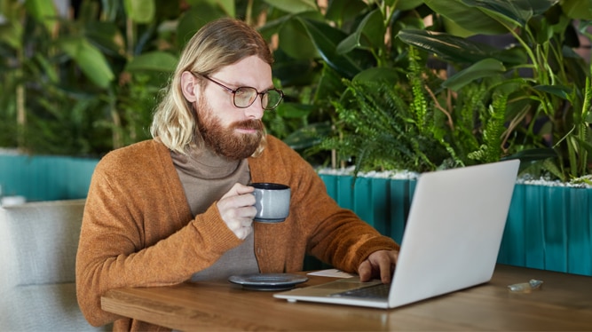 A man with long blonde hair and a beard sitting at a table in a café