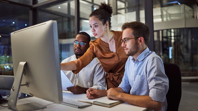 A team of three professionals collaborating at a desk