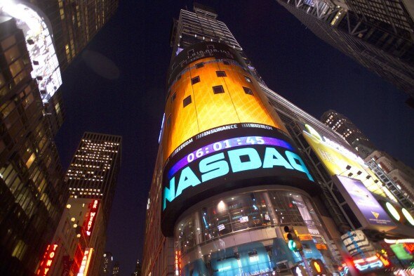 A view of the NASDAQ tower in Times Square at night,displaying a countdown timer and vibrant digital advertisements.