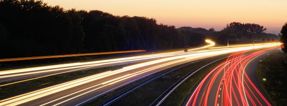 Long exposure shot of a highway with light trails from moving vehicles.