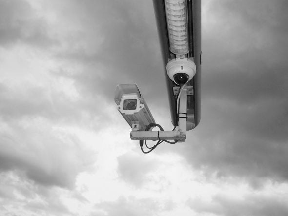 A black and white image of two security cameras mounted under a light fixture